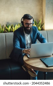 Happy Businessman  In Elegant Blue Suit Talking On Video Call Online Meeting With Colleagues On A Laptop Computer From A Restaurant