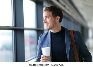 Happy Businessman Going To Work Drinking Coffee - Travel Lifestyle Or Morning Commute Urban Living. Young Professional Man Near Window In Office Building Or At Airport Terminal Business Class Flight.