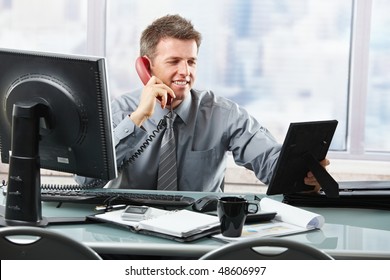 Happy Businessman Having Conversation On Landline Phone Looking At Family Photo Smiling.