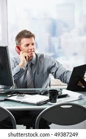 Happy Businessman Having Conversation On Landline Phone Looking At Family Photo Smiling.