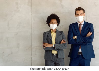 Happy businessman and his African American female colleagues wearing protective face masks while standing against the wall and looking at camera. Copy space. - Powered by Shutterstock