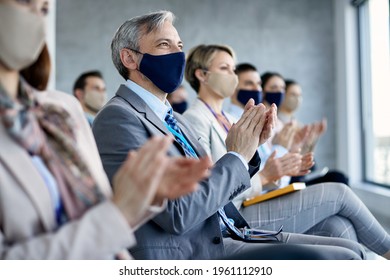 Happy Businessman And His Colleagues Applauding While Attending Training Class In Board Room And Wearing Face Masks Due To Coronavirus Pandemic.