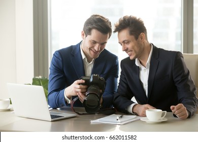 Happy businessman holding new professional camera, showing photographs to smiling colleague, partners viewing discussing pictures of business object, satisfied client looking at photos for project ads - Powered by Shutterstock