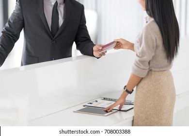 Happy Businessman In Hotel Check In At Reception Or Front Office Being Given Key Card. Classy Welcome Concept. Setup Studio Shooting.