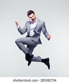 Happy businessman jumping in air over gray background