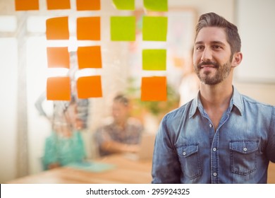 Happy Businessman Looking Post Its On The Wall In The Office