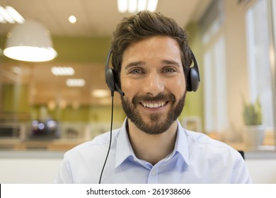 Happy Businessman in the office on the phone, headset, Skype. looking camera - Shutterstock ID 261938606