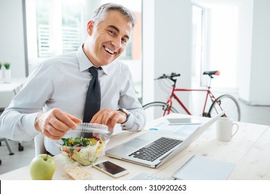 Happy Businessman Opening His Salad Pack And Having A Lunch Break At Office Desk