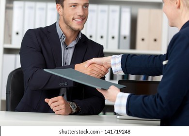 Happy businessman shaking hands with a female interviewer in office - Shutterstock ID 141719248