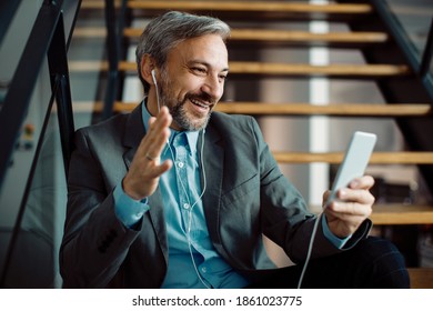 Happy businessman sitting on steps and talking to someone during a video call over smart phone. - Shutterstock ID 1861023775