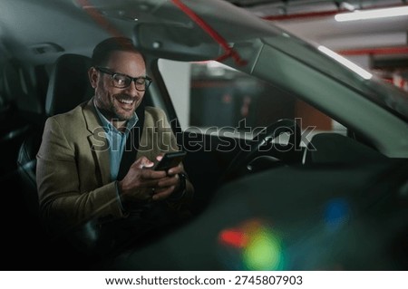 Happy businessman smiling while using smartphone in car, connecting and communicating online with technology