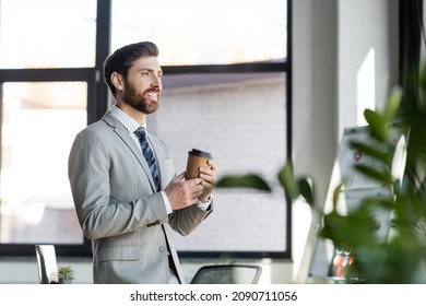 Happy businessman in suit holding coffee to go in office - Powered by Shutterstock