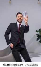 Happy Businessman Throwing Paper Plane In Office