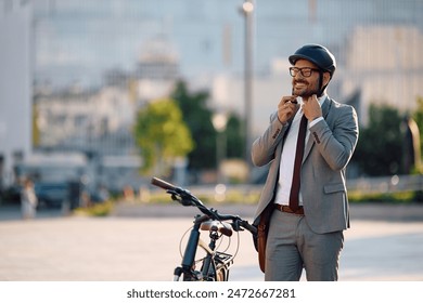 Happy businessman using cycling helmet while riding to work by bike. Copy space.  - Powered by Shutterstock