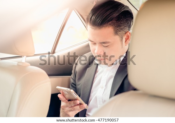 Happy\
businessman using smartphone calling while driving the car on his\
morning commute to work. Handsome Asian young man touching mobile\
phone on his luxury automobile on the road trip.\
