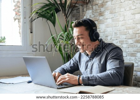 Happy businessman wearing headphones singing song at workplace, funny employee or freelancer using laptop, enjoying favorite track, listening to music, dancing, having fun during break