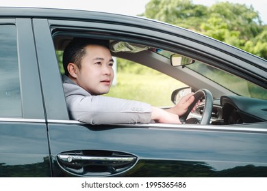 Happy Businessman While Driving The Car And Smiling On His Morning Commute To Work. Executive Handsome Asian Young Man On His Luxury Automobile On The Road Trip.