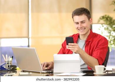 Happy Businessman Working Online With Multiple Devices And Holding A Smart Phone In A Desk At Office