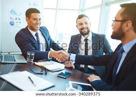 Happy businessmen handshaking after negotiation in office