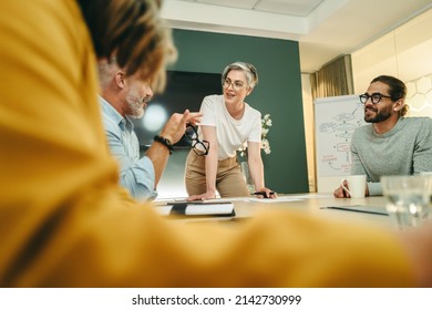 Happy businesspeople having a discussion in a boardroom. Group of cheerful business professionals sharing creative ideas during a meeting in a modern workplace.