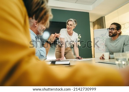 Happy businesspeople having a discussion in a boardroom. Group of cheerful business professionals sharing creative ideas during a meeting in a modern workplace.