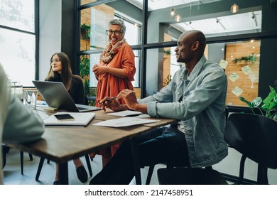 Happy businesspeople having a meeting in a creative office. Group of cheerful businesspeople working as a team in a multicultural workplace. - Shutterstock ID 2147458951