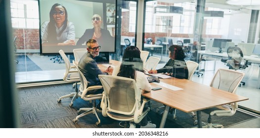 Happy Businesspeople Having A Virtual Briefing With Their Partners. Group Of Creative Businesspeople At A Meeting In A Boardroom. Team Of Global Businesspeople Communicating With Their Associates.