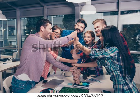 Happy businesspeople putting their fist on top of each other and laughing. They have training