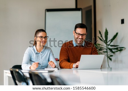 Happy businesspeople sitting by the desk and working together in the office