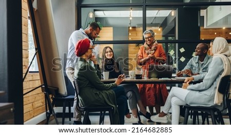 Happy businesspeople smiling cheerfully during a meeting in a creative office. Group of successful business professionals working as a team in a multicultural workplace.