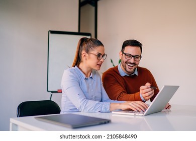 Happy businesspeople working together in the office while using laptop