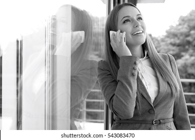 Happy Businesswoman Answering Cell Phone By Glass Door