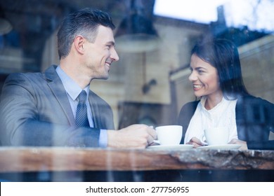Happy businesswoman and businessman having coffee break in cafe