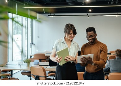 Happy Businesswoman and Businessman Using Digital Tablet Together at Work. 

Two smiling colleagues analyzing business report on a tablet while unrecognizable multi-ethnic team working at desk. - Powered by Shutterstock