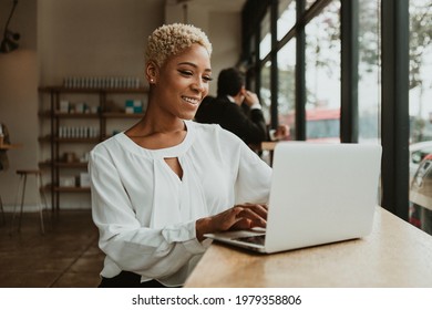 Happy businesswoman in a cafe using her laptop - Powered by Shutterstock