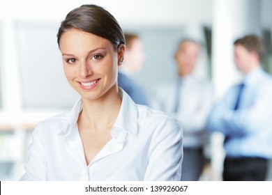 Happy businesswoman with colleagues in the background