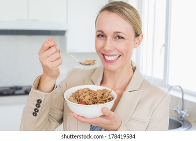 Femme d'affaires heureuse mangeant des céréales avant de travailler le matin à la maison dans la cuisine