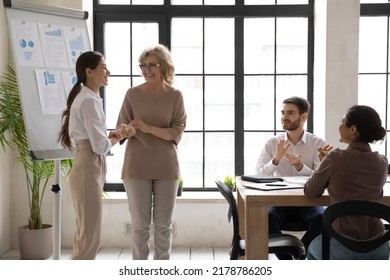 Happy Businesswoman Handshake Greeting New Employee Or Worker At Team Meeting In Office. Smiling Diverse Businesspeople Applaud Welcome Newcomer Newbie To Team At Briefing. Recruitment Concept.