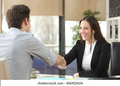 Happy businesswoman handshaking with client closing deal in an office interior with a window in the background - Powered by Shutterstock