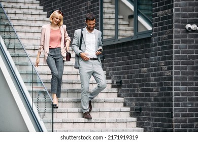 Happy businesswoman and her male colleague walking downstairs outdoors.  Copy space.