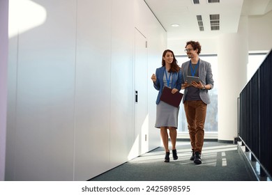 Happy businesswoman and her male colleague communicating in office building hallway. Copy space.  - Powered by Shutterstock