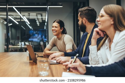Fröhliche Geschäftsfrau lacht, während sie ein Treffen mit ihren Kollegen leitet. Eine Gruppe verschiedener Geschäftsleute, die an einem modernen Arbeitsplatz zusammenarbeiten. Geschäftskollegen, die an einem Projekt mitarbeiten.