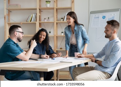 Happy businesswoman manager laughing at joke in boardroom at meeting. Smiling fun mentor coach lead presentation new project for diverse colleagues in conversation at negotiation. - Shutterstock ID 1733598056