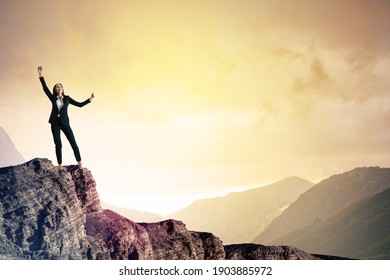 Happy businesswoman on cliff with clouds and copy space. Celebration and victory concept