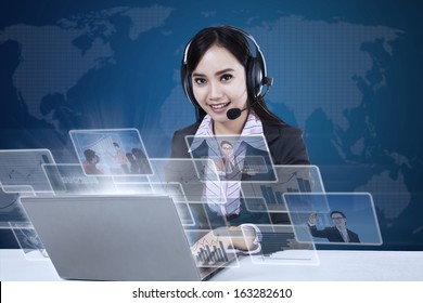 Happy businesswoman with pictures interface in front of laptop on world map background