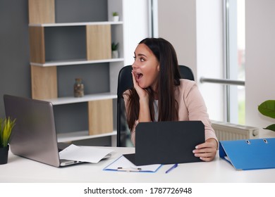 Happy Businesswoman With Raised So Hand Gesture Reading Letter On Desk In Front Of Laptop. The Businessman Is Satisfied With The Good News From The Correspondence.