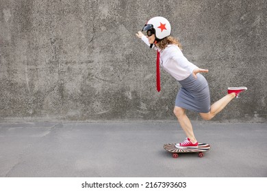 Happy businesswoman riding skateboard. Outdoor portrait of young woman. Back to work, start up and business idea concept