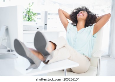 Happy businesswoman sitting with her feet up in her office