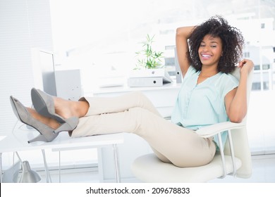 Happy Businesswoman Sitting With Her Feet Up In Her Office