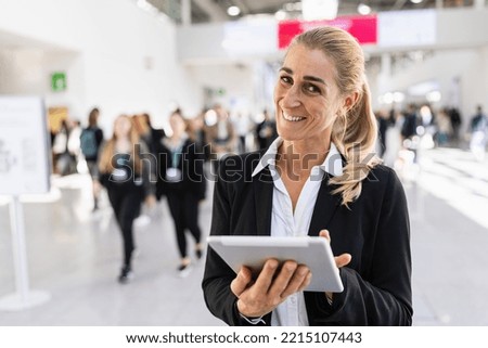 happy businesswoman at a trade fair holding tablet